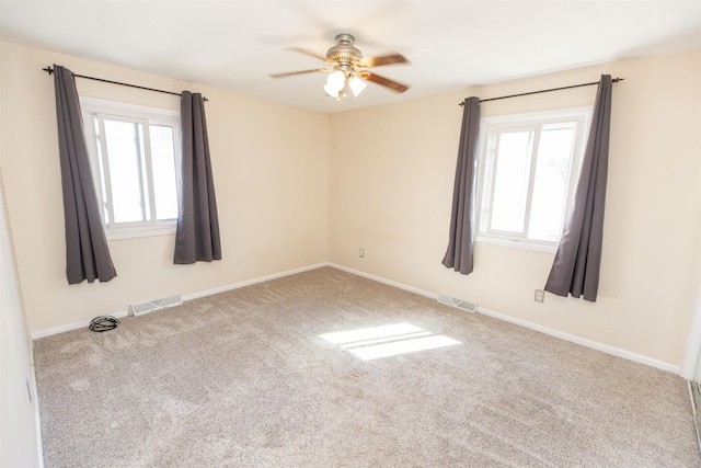 carpeted empty room with visible vents, baseboards, and a ceiling fan