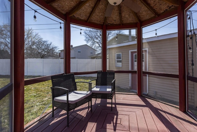 sunroom / solarium featuring a healthy amount of sunlight, ceiling fan, and vaulted ceiling