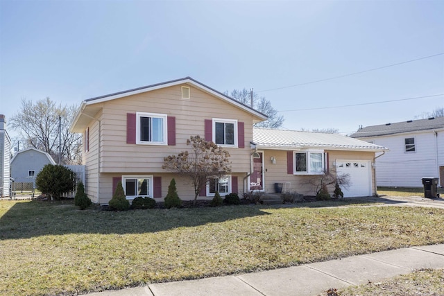 split level home with a front yard, concrete driveway, a garage, and metal roof