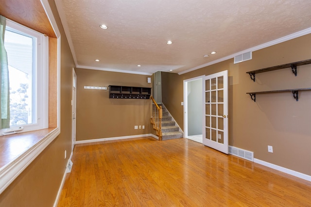 spare room featuring crown molding, stairway, wood finished floors, and visible vents