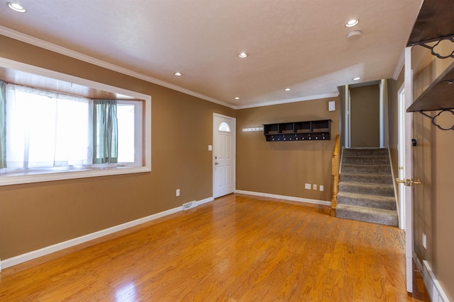 foyer entrance with light wood-type flooring, visible vents, crown molding, baseboards, and stairs