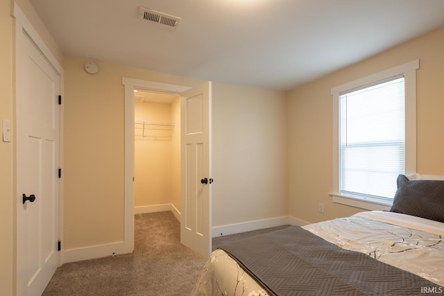 carpeted bedroom featuring visible vents, baseboards, a closet, and a spacious closet