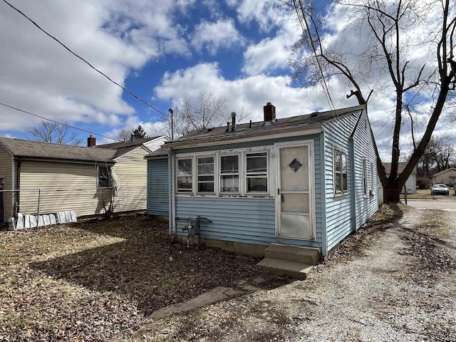 back of property with entry steps and a chimney