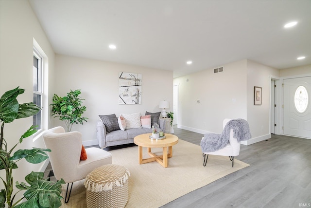 living area featuring light wood-style flooring, recessed lighting, visible vents, and baseboards