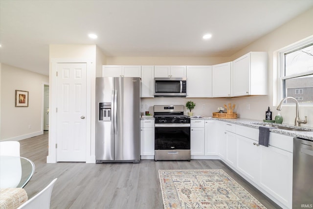 kitchen featuring recessed lighting, light wood-style floors, white cabinets, stainless steel appliances, and a sink