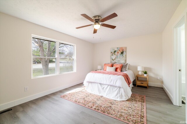 bedroom featuring visible vents, baseboards, light wood-type flooring, and ceiling fan