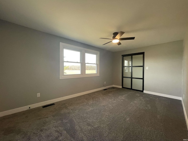 unfurnished room featuring a ceiling fan, visible vents, dark carpet, and baseboards