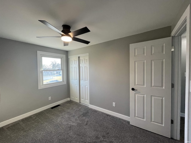 unfurnished bedroom featuring visible vents, a ceiling fan, a closet, dark colored carpet, and baseboards