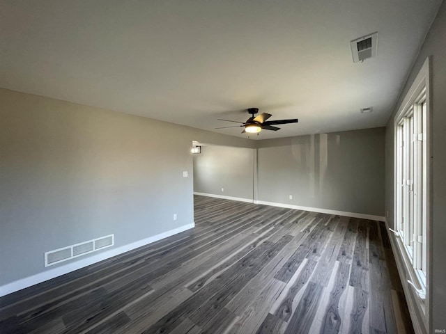 unfurnished room featuring dark wood-type flooring, baseboards, visible vents, and ceiling fan