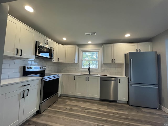 kitchen with visible vents, light countertops, white cabinets, stainless steel appliances, and a sink