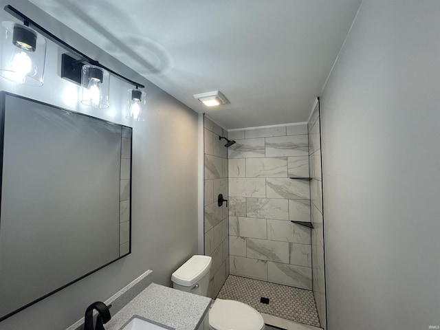 bathroom with vanity, toilet, and tiled shower