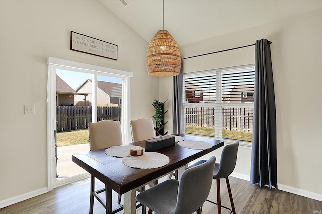 dining area with lofted ceiling, a healthy amount of sunlight, and wood finished floors