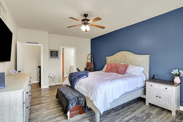 bedroom featuring a ceiling fan, wood finished floors, baseboards, and ensuite bathroom