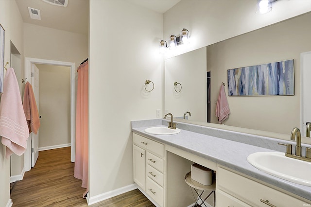 full bathroom featuring double vanity, wood finished floors, visible vents, and a sink