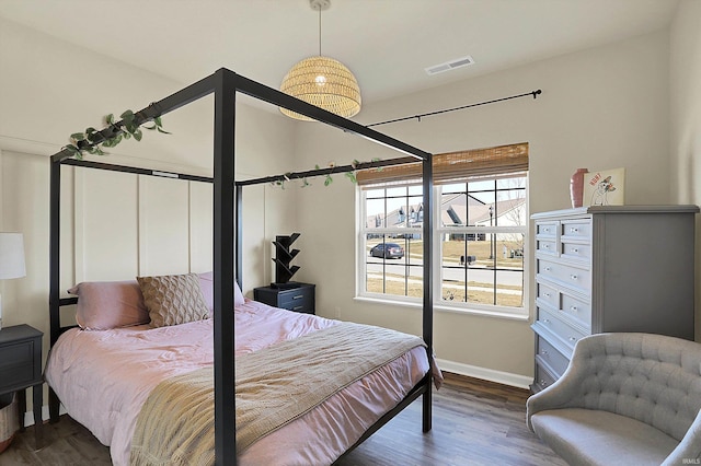 bedroom with visible vents, baseboards, and wood finished floors