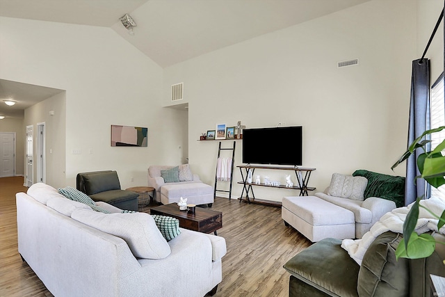 living area with visible vents, high vaulted ceiling, and wood finished floors