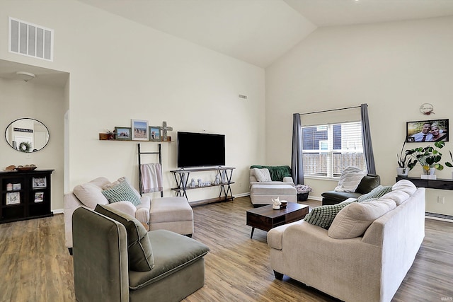 living area with visible vents, high vaulted ceiling, baseboards, and wood finished floors