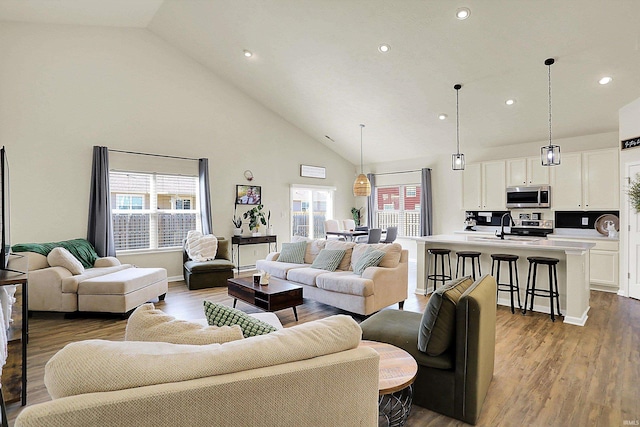 living area featuring recessed lighting, wood finished floors, baseboards, and high vaulted ceiling