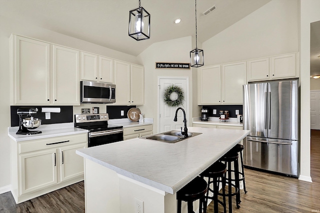 kitchen with white cabinets, appliances with stainless steel finishes, an island with sink, and a sink