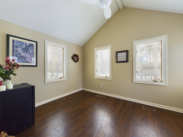 spare room with dark wood-type flooring, visible vents, and lofted ceiling