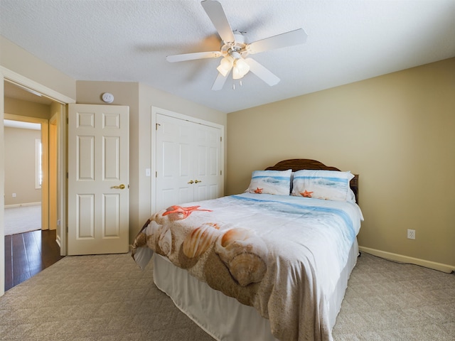 bedroom with carpet, baseboards, ceiling fan, a closet, and a textured ceiling