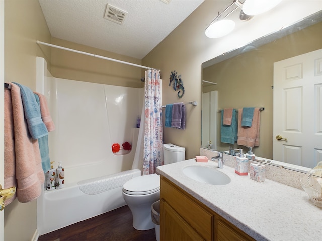 bathroom with visible vents, toilet, vanity, shower / tub combo, and a textured ceiling