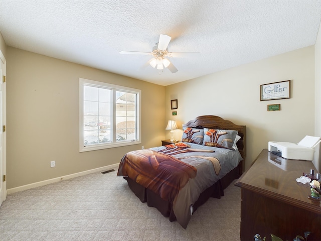 carpeted bedroom with visible vents, baseboards, a textured ceiling, and ceiling fan