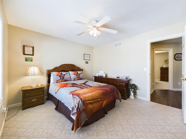 bedroom featuring visible vents, a textured ceiling, carpet floors, baseboards, and ceiling fan