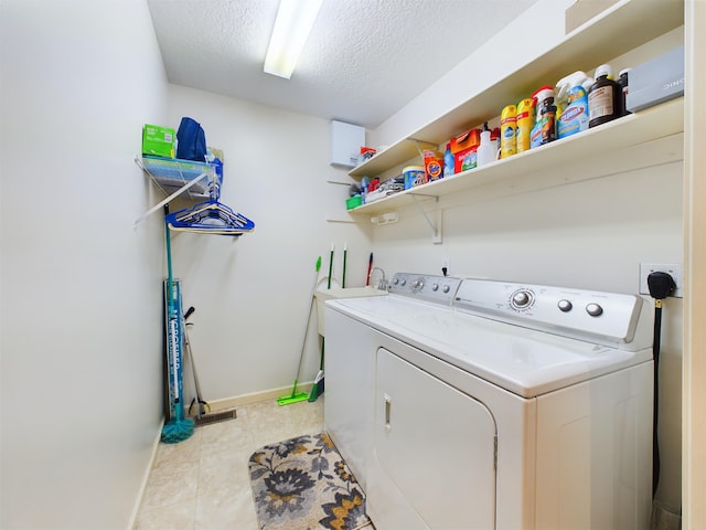 laundry area featuring baseboards, a textured ceiling, washing machine and dryer, and laundry area