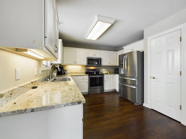 kitchen with a sink, stainless steel appliances, light stone counters, and white cabinetry