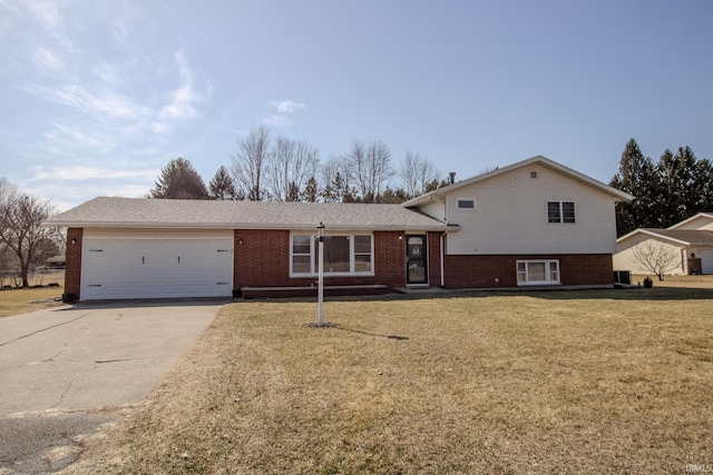 tri-level home with concrete driveway, an attached garage, brick siding, and a front lawn