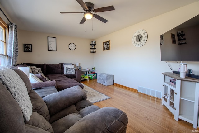 living area featuring visible vents, baseboards, a ceiling fan, and wood finished floors