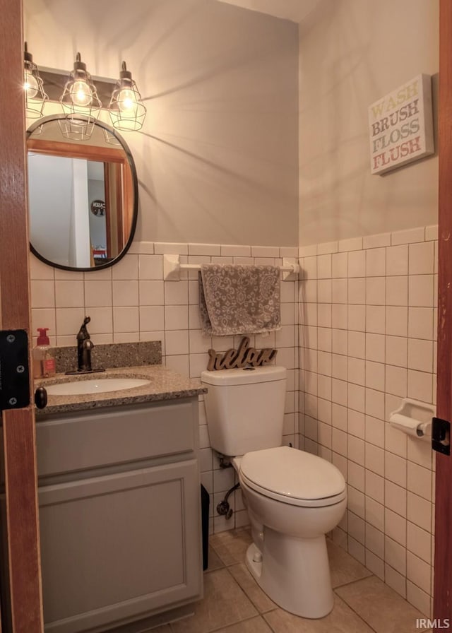 bathroom with tile patterned flooring, tile walls, toilet, and vanity