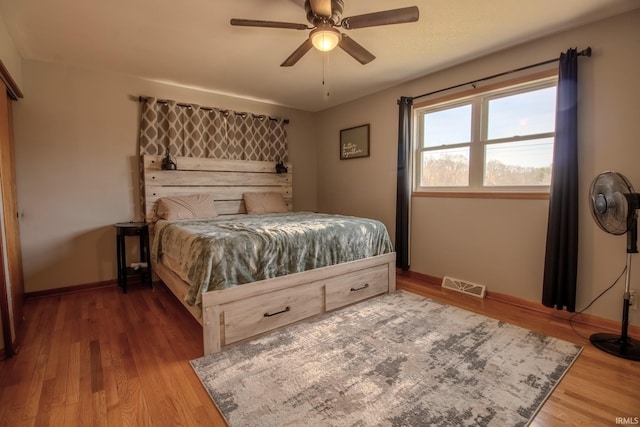 bedroom featuring visible vents, baseboards, wood finished floors, and a ceiling fan