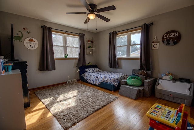 bedroom with visible vents, multiple windows, baseboards, and wood finished floors