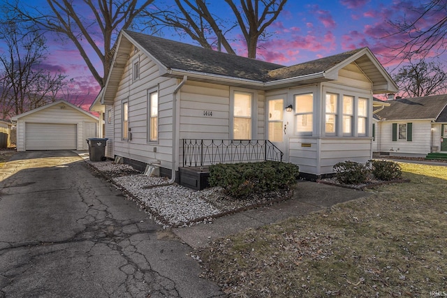 view of front facade with aphalt driveway, covered porch, a detached garage, and an outdoor structure