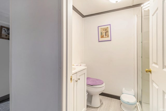 bathroom with crown molding, toilet, vanity, and baseboards