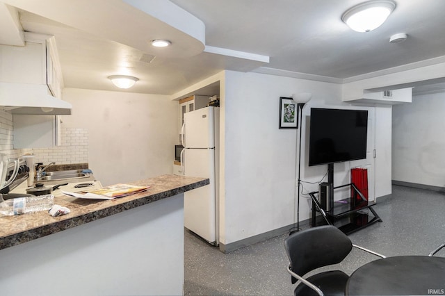 kitchen with backsplash, baseboards, freestanding refrigerator, speckled floor, and a sink