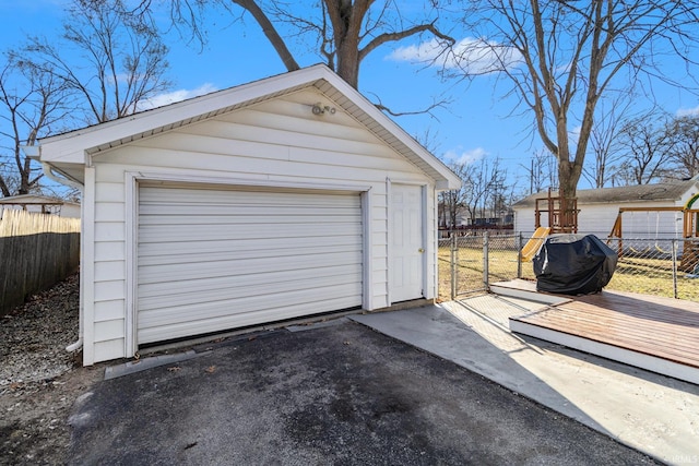 detached garage featuring driveway and fence