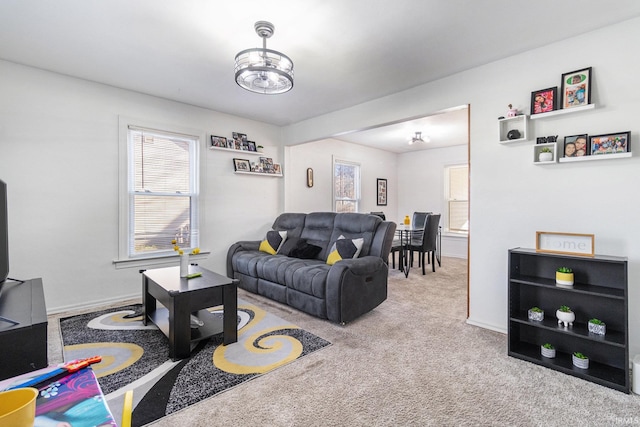 carpeted living room with a notable chandelier and baseboards