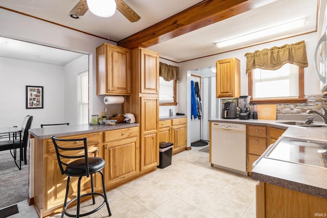 kitchen featuring ceiling fan, dishwasher, a breakfast bar, a peninsula, and a sink