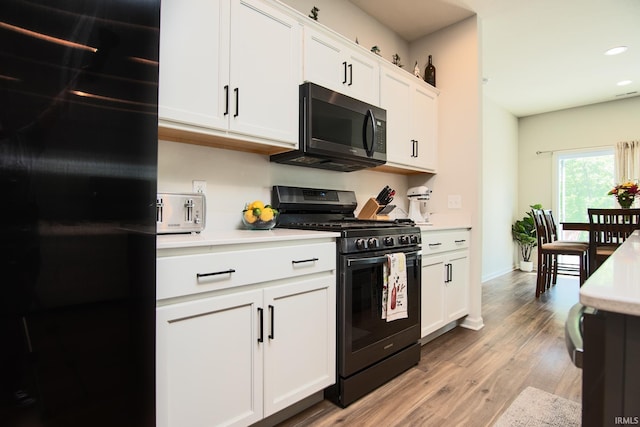 kitchen with light wood finished floors, light countertops, recessed lighting, white cabinets, and black appliances