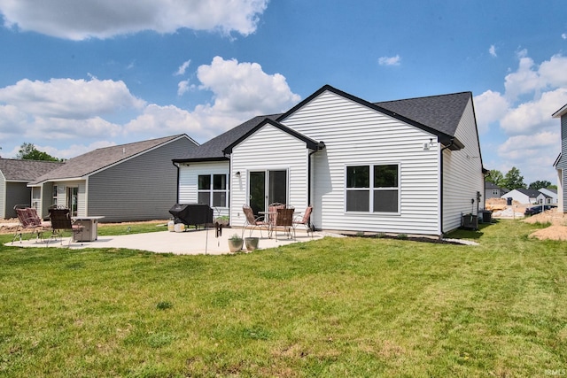 back of house featuring a yard, central AC unit, a shingled roof, and a patio area