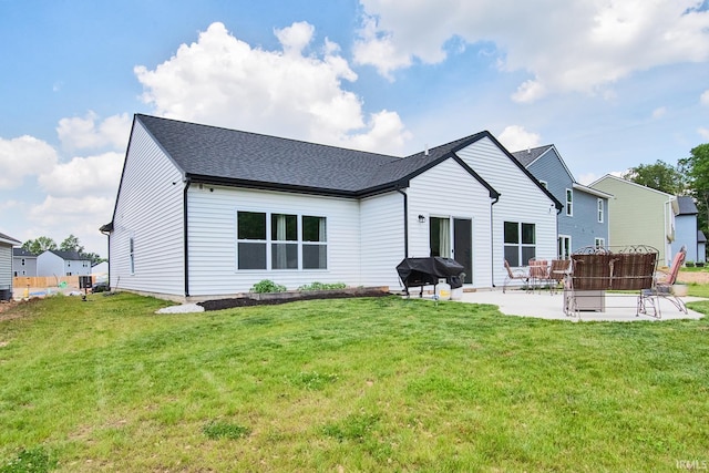 back of property featuring a patio, a lawn, and roof with shingles