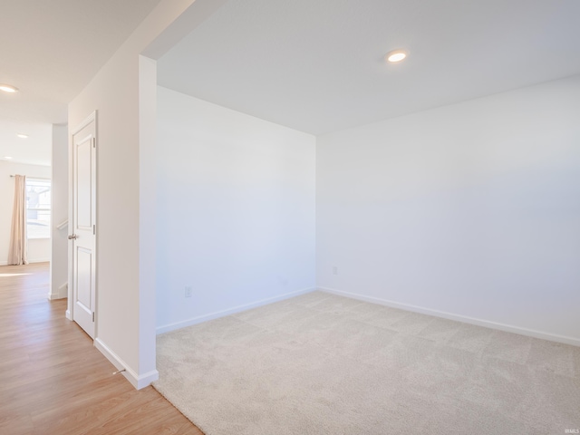 unfurnished room featuring recessed lighting, baseboards, light wood finished floors, and light carpet