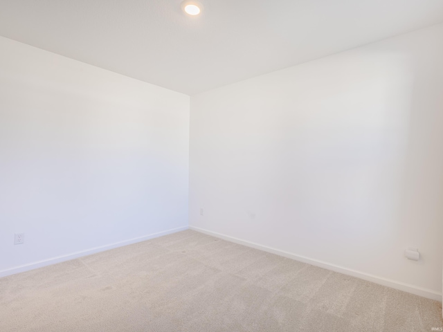 spare room with baseboards and light carpet