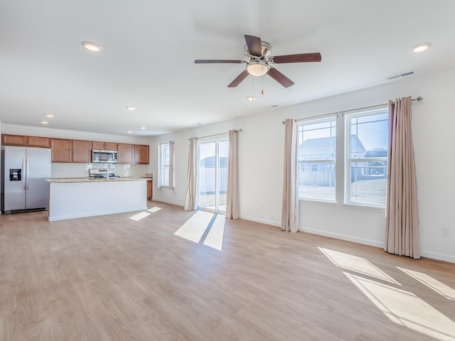 unfurnished living room featuring a wealth of natural light, visible vents, and light wood finished floors