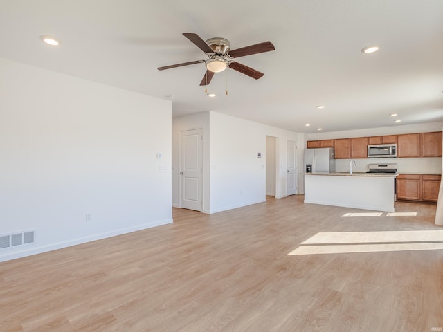 unfurnished living room featuring a ceiling fan, visible vents, baseboards, recessed lighting, and light wood-style floors