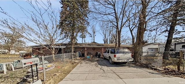 view of front facade with brick siding, driveway, and fence