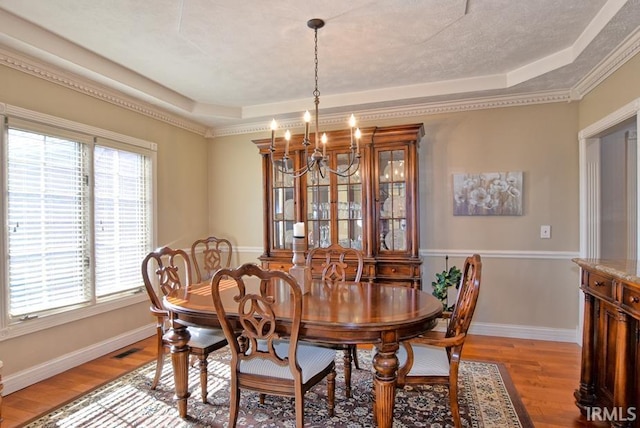 dining room featuring visible vents, a tray ceiling, light wood-style floors, an inviting chandelier, and baseboards